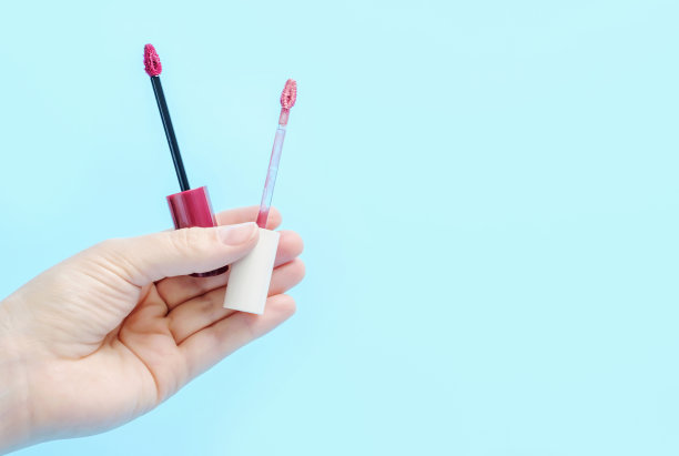 女性手握口红刷特写在蓝色背景复制空间。图片下载