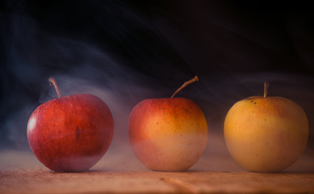 苹果就像魔法中的烟雾，新鲜的苹果放在桌子上，黑色的背景上充满了魔法的烟雾图片下载