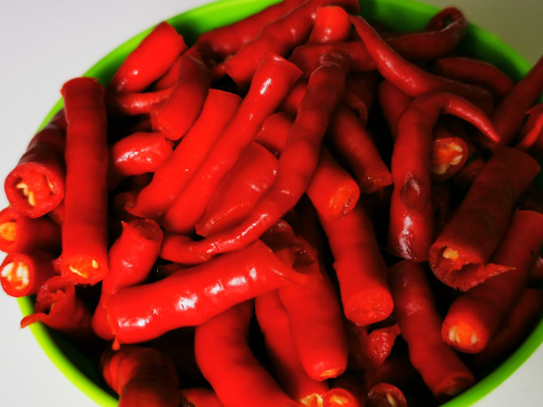 切成一束卷曲的红辣椒，放入有白色底色的绿碗中图片下载