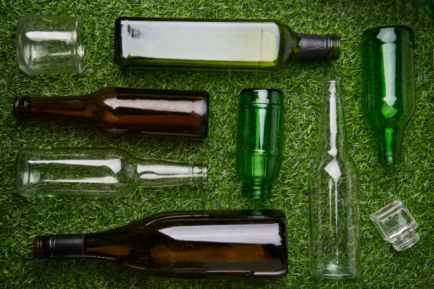 玻璃垃圾单独收集。可回收玻璃废料的绿色草地背景。图片下载