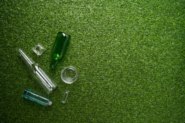 玻璃垃圾单独收集。可回收玻璃废料的绿色草地背景。图片下载