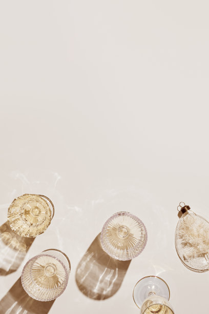 新年假期平铺，白色气泡酒在不同的水晶酒杯，节日香槟饮料，米色金色的美学布局，新年假期活动或派对的概念，阴影图片下载