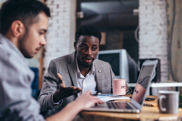 年轻的商人与他的商业伙伴坐在咖啡馆的笔记本电脑上工作。图片下载