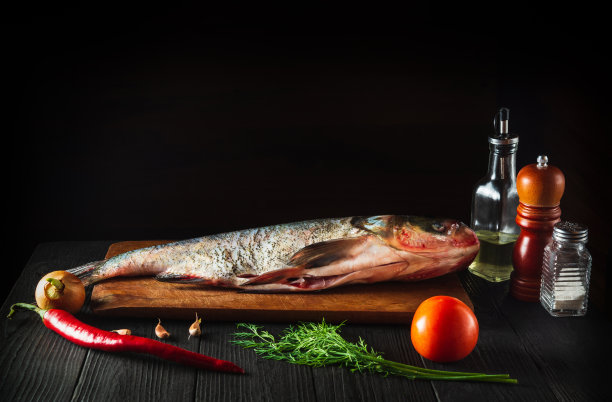烹饪前将鳙鱼和蔬菜一起放在砧板上。餐厅厨房里的生去皮鱼。鱼类饮食理念图片下载