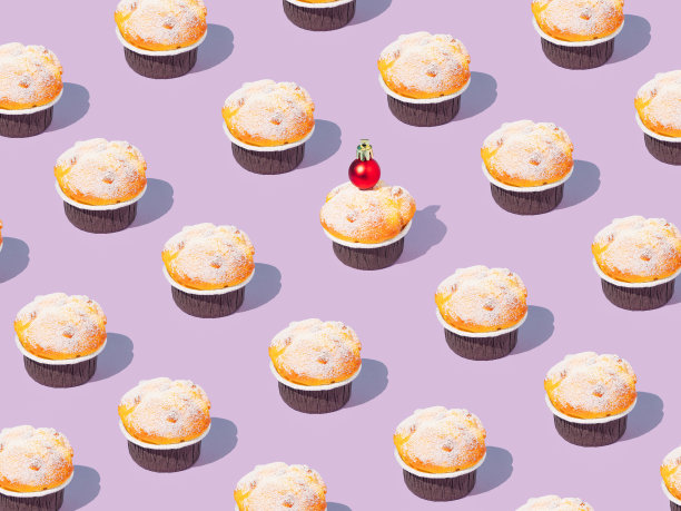 用闪闪发光的红色圣诞小玩意装饰的纸杯蛋糕的创意图案。时髦的概念，拼贴在紫色粉彩背景。创意艺术极简美学。副本的空间。图片下载