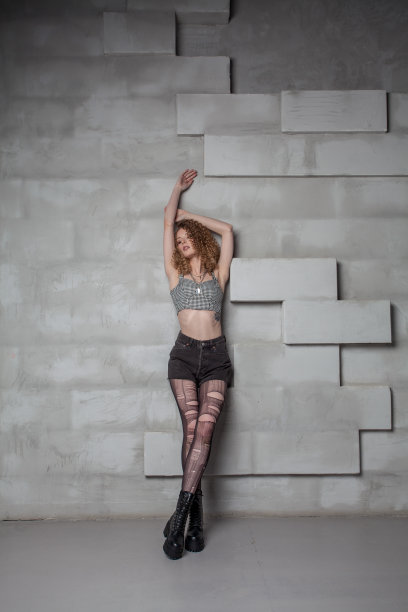 美丽迷人的grunge女人撕裂紧身衣和修剪头发站在工作室图片下载