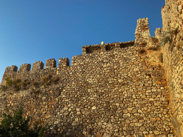 一座古老的中世纪堡垒的巨大石墙，由鹅卵石砌成，映衬着蓝天图片下载