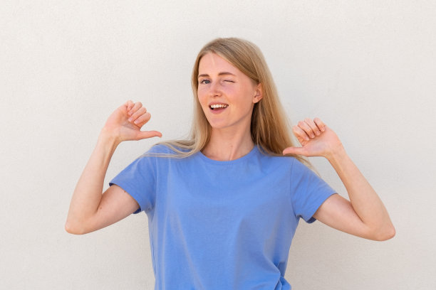 眨眼的年轻女子指着自己的大拇指图片下载