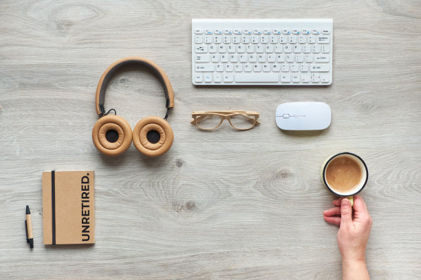 大不退休趋势的不退休概念形象。平铺着现代办公用品——笔记本、老花镜、电脑键盘、鼠标。带文字的纸，标题未退休。成熟工人握着咖啡的手。图片下载