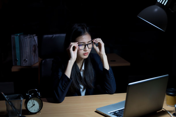 亚洲女人晚上在黑暗的办公室工作。亚洲女商人在灯光下加班图片下载