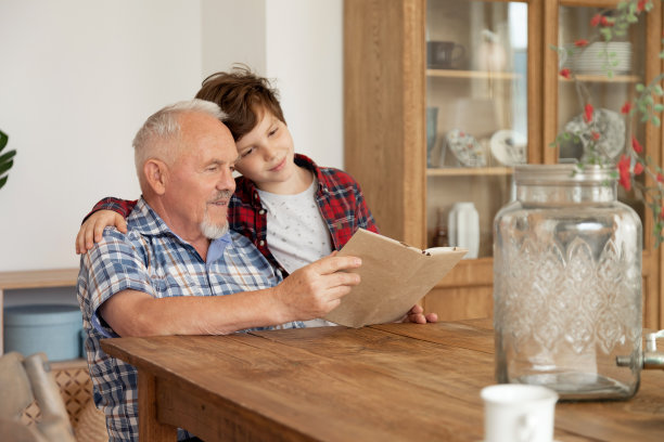 爷爷在舒适的厨房里给可爱的孙子读书图片下载
