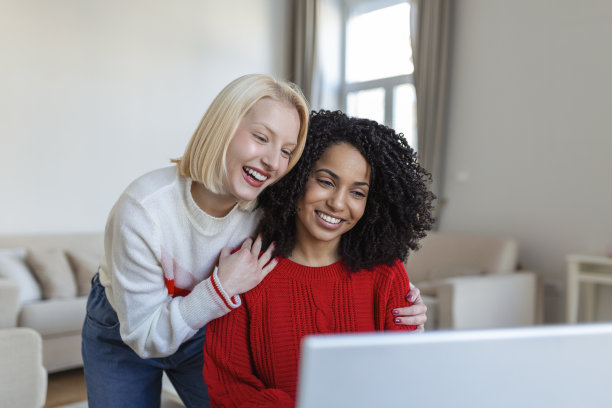 两个漂亮的女人用笔记本电脑进行在线视频通话，并与朋友在线敬酒。朋友在线聚会。图片下载