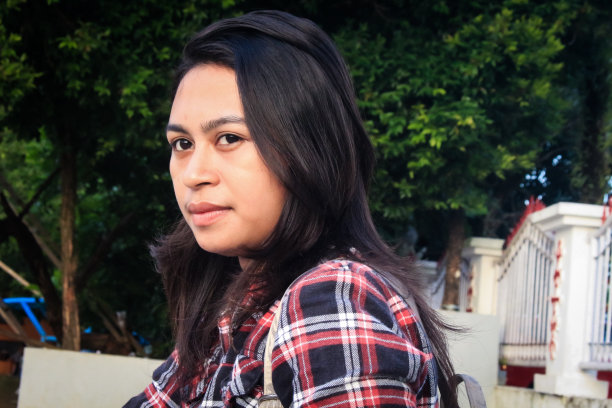 风景照片，一个美丽的女人坐在公园里，背景是树木和栅栏图片下载