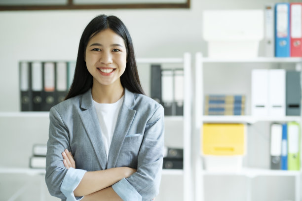 特写自信的女人双臂交叉对着相机微笑的肖像。图片下载