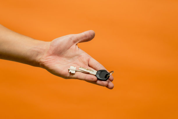 男子的手与钥匙隔离在橙色背景图片下载