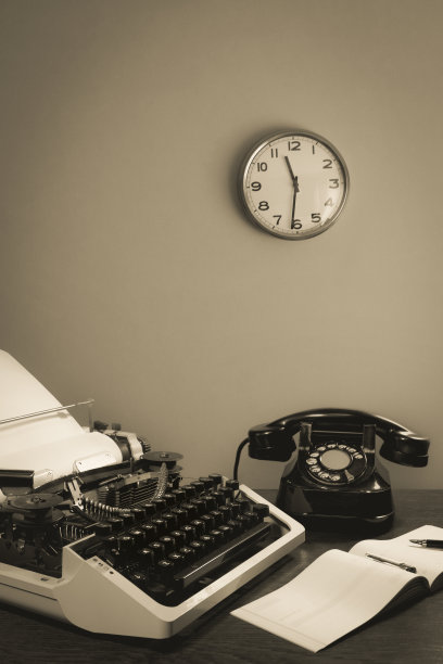 桌上放着一台老式打字机和一部旧电话，还有一本支票簿和一支钢笔。墙上的钟。黑白两色图片下载