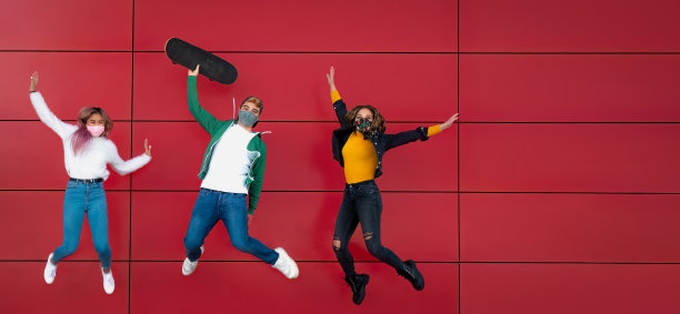 多民族的ersasmus青少年学生带着面具在空中跳跃庆祝图片下载