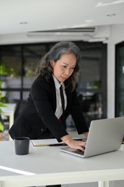 专业的亚裔女性高级经理，在桌子上学习，使用笔记本电脑，在办公室工作。图片下载