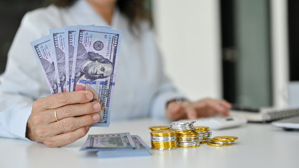 特写图片，一个成功的亚洲老妇人拿着桌上的美元。图片下载