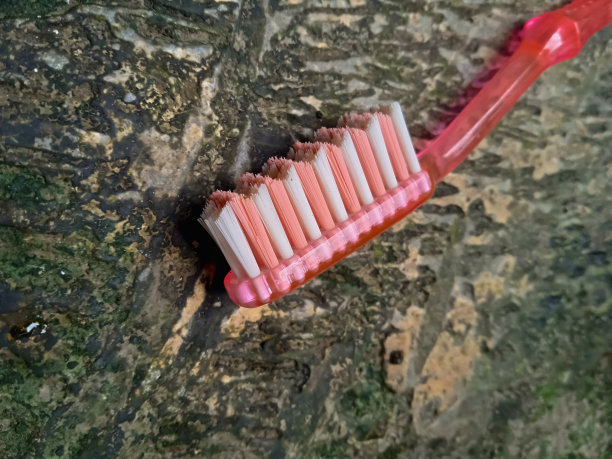 一张放在脏地板上没用过的牙刷的照片。图片下载