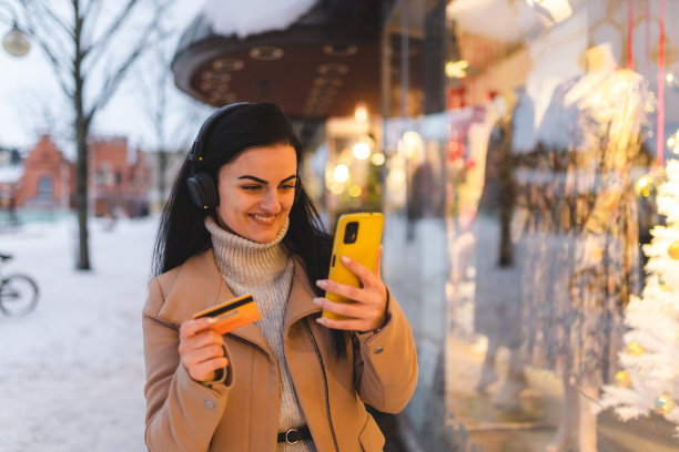 年轻漂亮的女人用她的信用卡用她的手机在网上购物图片下载