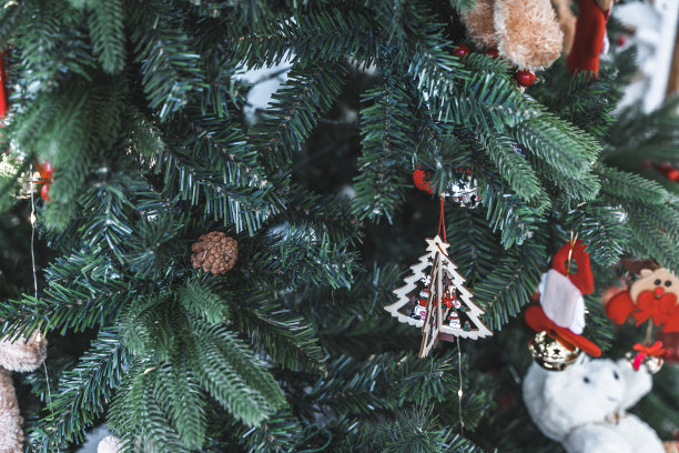 圣诞快乐，近距离彩色球，礼品盒和圣诞祝福图片包裹，泰迪熊装饰在绿色圣诞树背景装饰在圣诞节和新年。图片下载