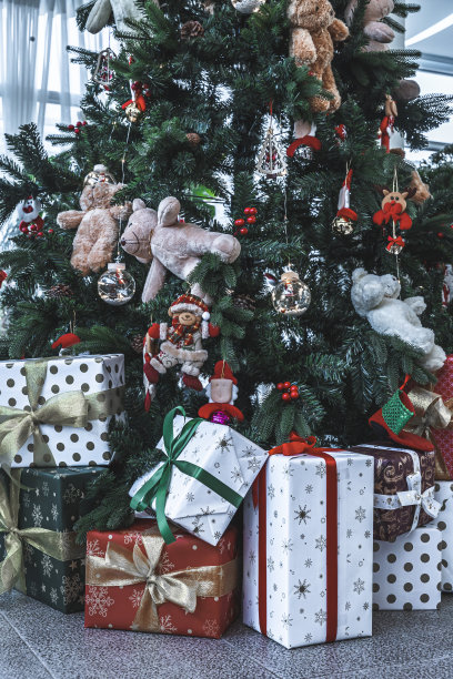 圣诞快乐，近距离彩色球，礼品盒和圣诞祝福图片包裹，泰迪熊装饰在绿色圣诞树背景装饰在圣诞节和新年。图片下载