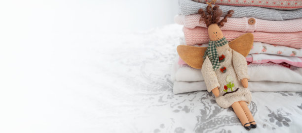 一堆粉红色和灰色的婴儿用品和一个天使玩具在灰色和白色的背景上复制空间。新生儿用的东西都是天然的，生物纯净的材料。图片下载