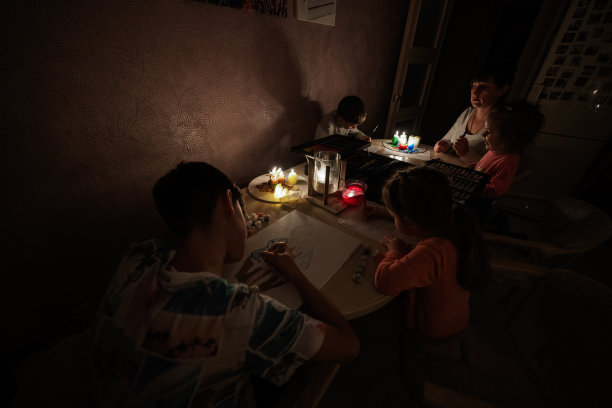 在欧洲能源危机导致停电期间，一家人聚在一起。孩子们在黑暗中画画。图片下载