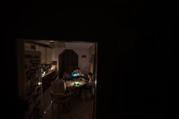 在欧洲能源危机导致停电期间，一家人聚在一起。孩子们在黑暗中画画。图片下载