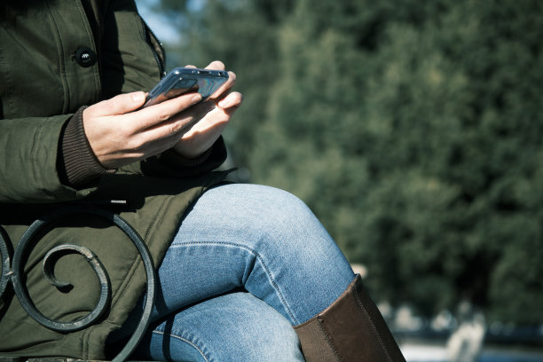 在冬季小镇，一个女人用智能手机的手图片下载