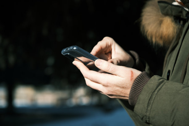 在冬季小镇，一个女人用智能手机的手图片下载