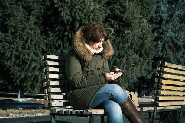 女子在冬季小镇使用智能手机图片下载