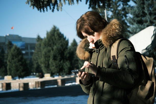 女子在冬季小镇使用智能手机图片下载
