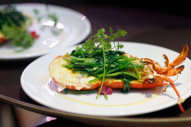 龙虾装在盘子里，切成两半，填上菠菜和蔬菜图片下载