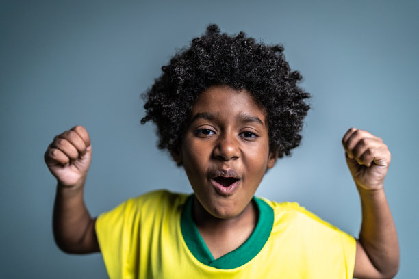 男孩的肖像庆祝穿着巴西队的颜色在灰色背景图片下载
