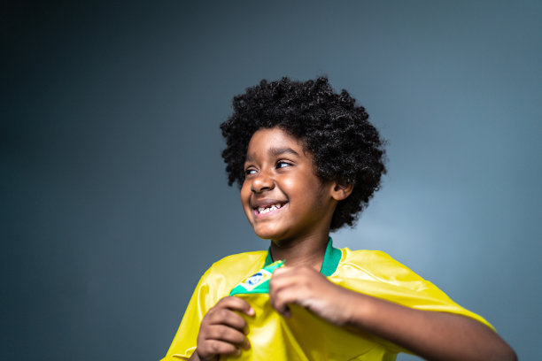 快乐的骄傲男孩穿着巴西队的颜色在灰色背景图片下载