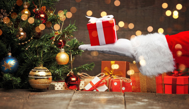 圣诞老人手拿包装好的圣诞礼物。图片下载