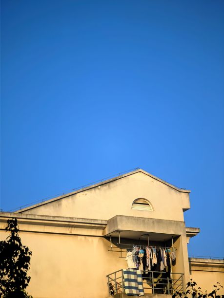 垂直拍摄风化的建筑侧面，在无云的天空下挂着衣服图片下载