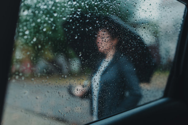 女商人打着伞在雨中等在车外图片下载