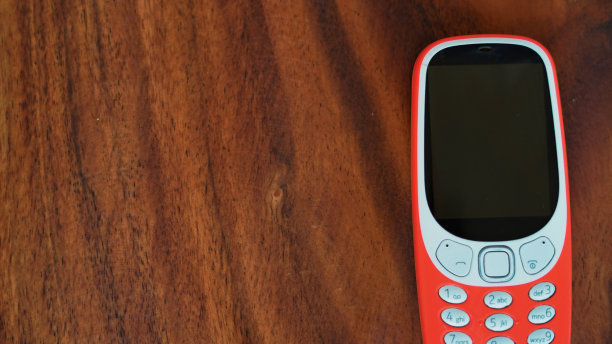 一个键盘电话与按钮隔离在黑色背景。黑色显示屏的旧手机。印度2g、3g橙色手机特写。技术和社会观念。图片下载