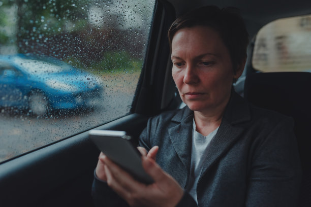 下雨的时候，女商人坐在汽车后座发短信图片下载