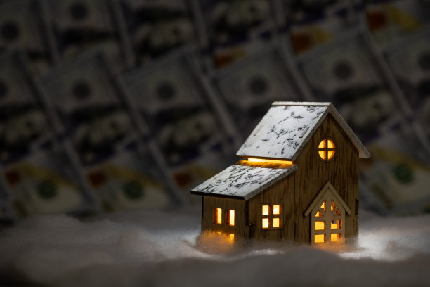 一个具有象征意义的木制房子，明亮的窗户，背景是100美元钞票图片下载