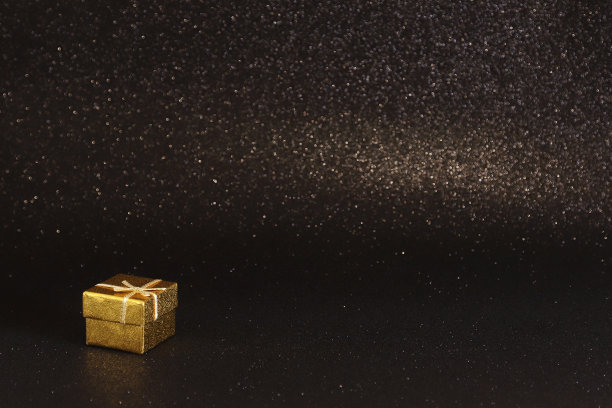 金色礼盒上的黑色闪闪发光的背景。照片与选择性对焦。带有复制空间的背景图片下载