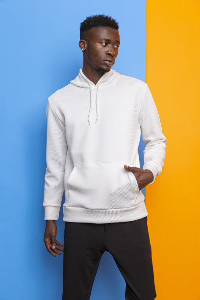 穿着运动衫的黑人模特在蓝色和橙色的墙前拍摄时装。图片下载