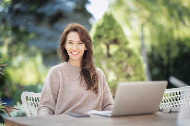 快乐的中年妇女在户外使用笔记本电脑图片下载