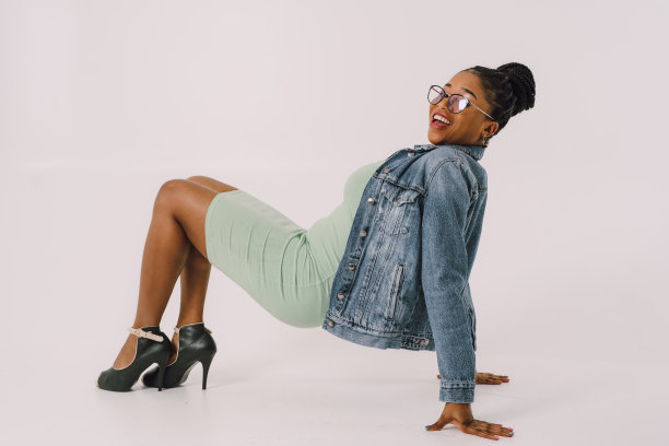 开朗的年轻女子在一件连衣裙与牛仔夹克的股票照片图片下载