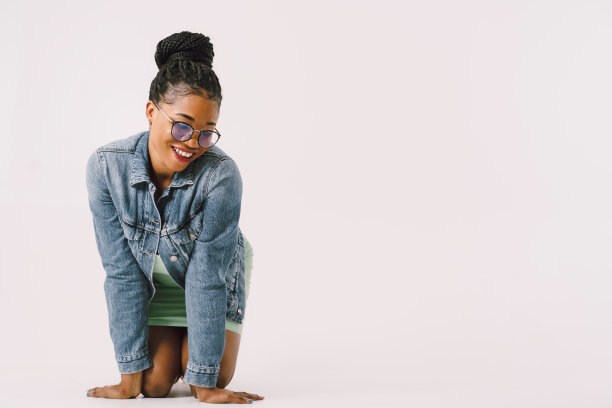 欢快的年轻女子在一件连衣裙和牛仔夹克跪在地板上的股票照片图片下载