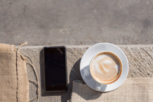 卡布奇诺和智能手机在人行道上。图片下载