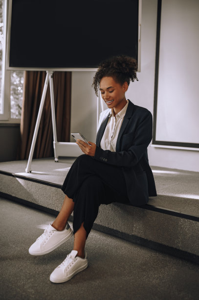 女人坐在办公室地板上看智能手机图片下载